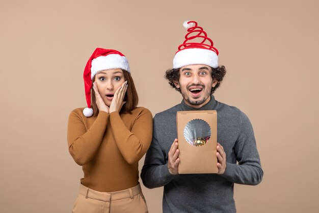 Festive mood with excited cool couple wearing red santa claus hats on gray stock image