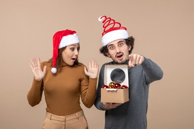 Festive mood with excited cool couple wearing red santa claus hats guy opening boxon gray footage