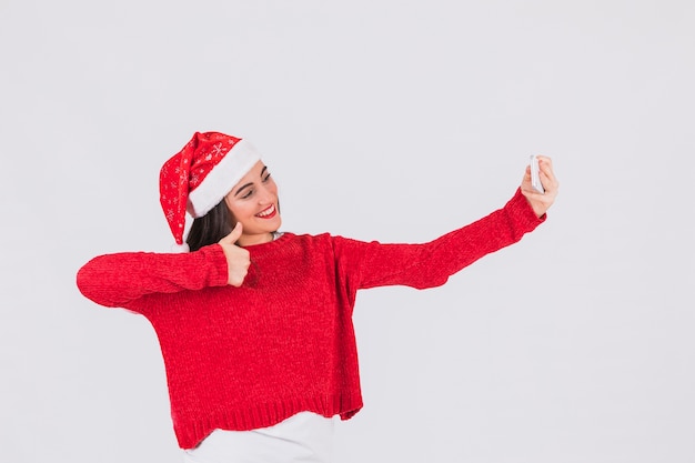 Festive woman in Christmas hat posing for selfie 