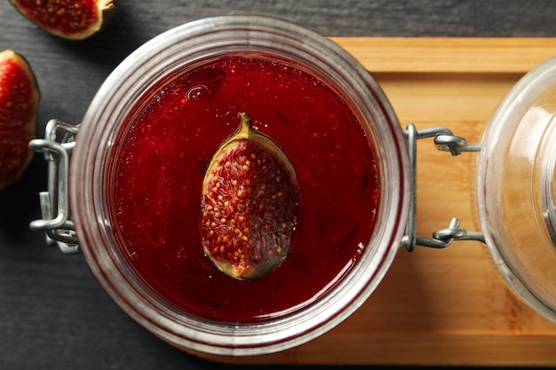 Free Photo figs and jar of jam in wooden stand on gray background close up