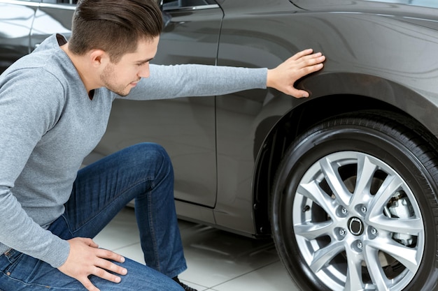 Free photo final check horizontal portrait of a man checking tires on his new car