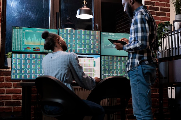 Free Photo financial analysts near multi monitor workstation using tablet device to analyze capital profit risks. hedge fund company professional agents in office, reviewing trading strategies to take profits.