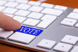 Free photo finger pressing on vote blue button on keyboard. online elections