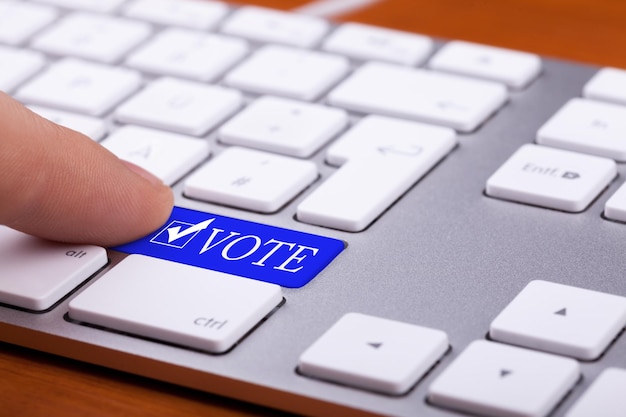 Free photo finger pressing on vote blue button and symbol on keyboard. online elections