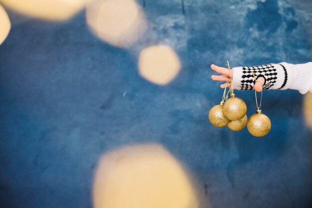 Fingers holding golden christmas balls