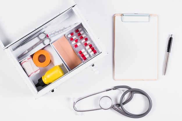 Free photo first aid kit with clipboard; stethoscope and pen on white background