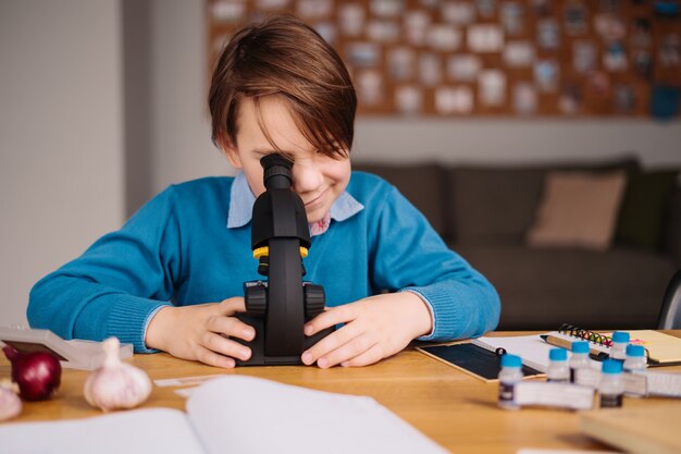 First grade boy studying at home using microscope