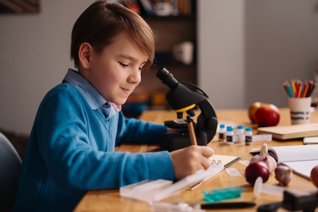 First grade boy studying at home using microscope