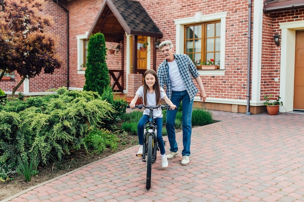 Free photo first lessons cycling riding. handsome grandather teach his granddaughter against.