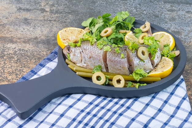 Free photo fish and vegetables on a wooden pan, on a towel.