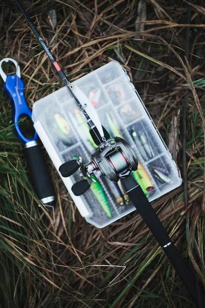 Free photo fishing rod over the fishing lure transparent plastic box on grass