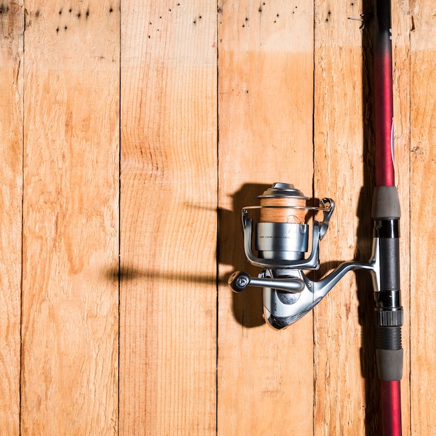 Fishing rod with fishing reel on wooden desk