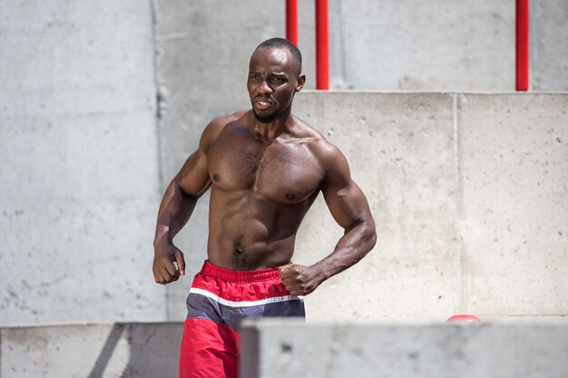 fit athlete doing exercises at stadium. Afro or african american man outdoor at city