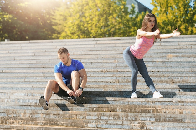 Fit fitness woman and man doing stretching exercises outdoors at park