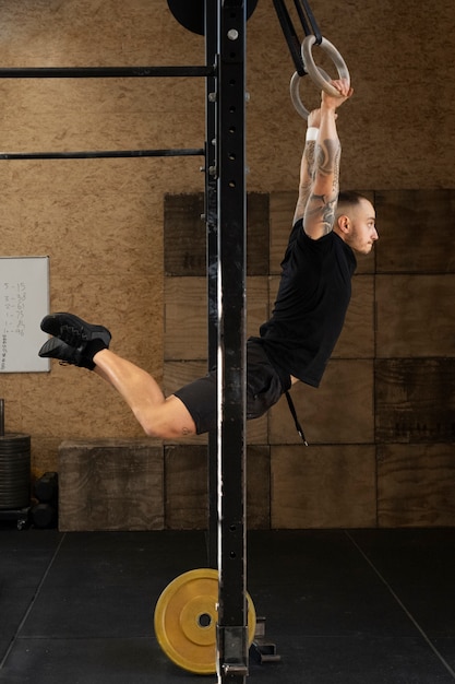 Free photo fit man exercising at gym full shot