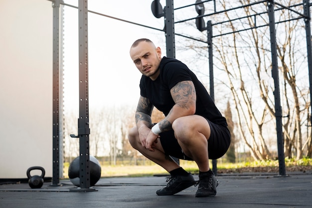 Fit man sitting outdoors full shot