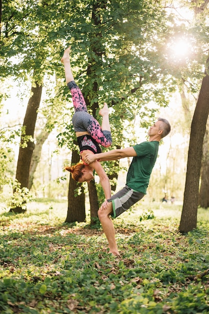 Fit mid adult couple doing acroyoga balance in nature