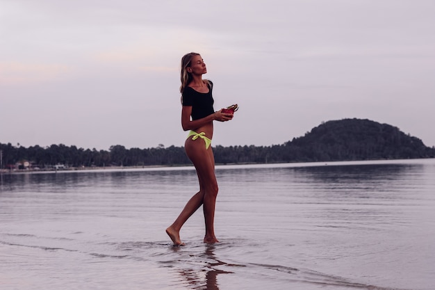 Fit tanned young caucasian Woman in sea at sunset