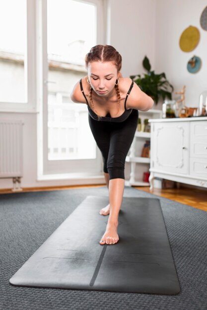 Fit woman doing yoga at home front view