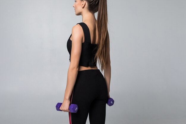 Fit woman with dumbbell over white wall