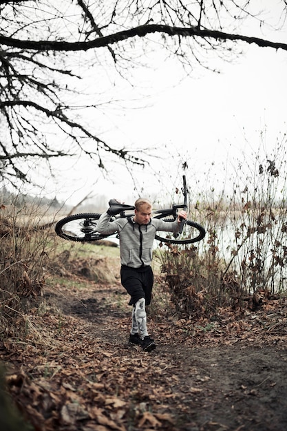 Free photo fit young man walking with bicycle on trail