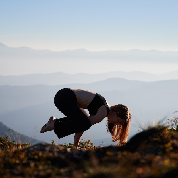 Fit young woman doing yoga exercise in mountains