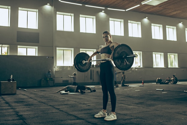 Free Photo fit young woman lifting barbells working out in a gym