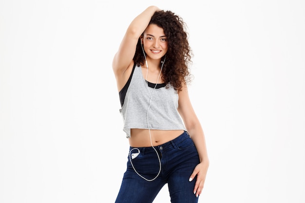 Fitness curly girl listening to music and posing