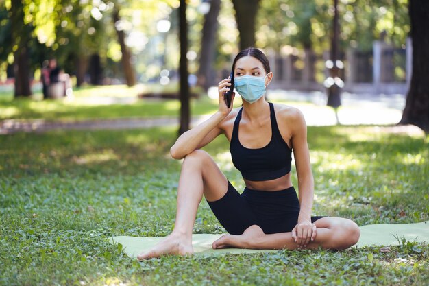 Fitness girl with a smartphone on nature, enjoys sports training