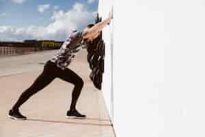 Free photo fitness man doing push-ups against wall