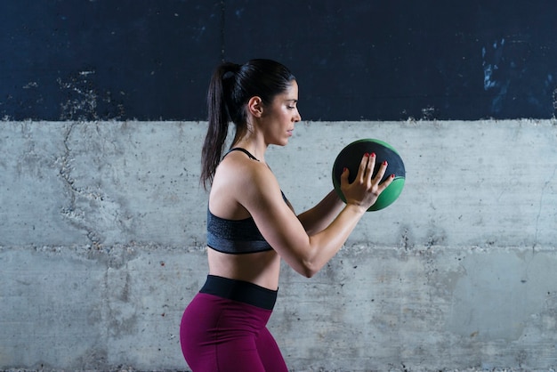 Free Photo fitness woman holding medicine ball and exercising in the gym