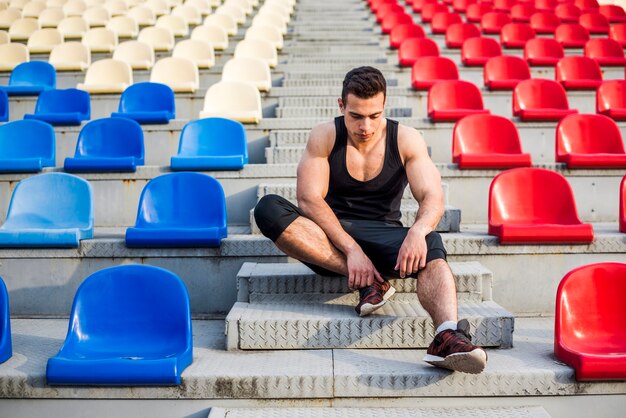 Fitness young male athlete relaxing on the bleacher