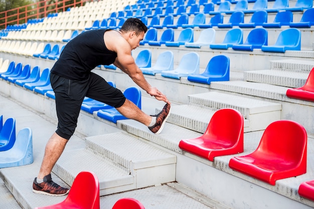 Free Photo fitness young man stretching his leg on bleacher