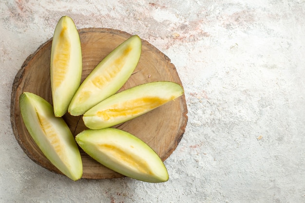 Free photo five slices of melon on wooden platter on left side of marble ground