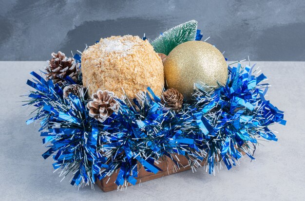 Flaky cake nested on a bundle of christmas decorations on marble surface