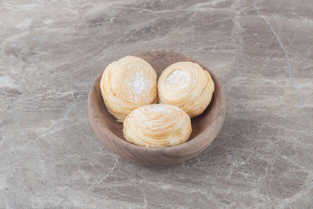 Flaky cookies in a small bowl on marble surface