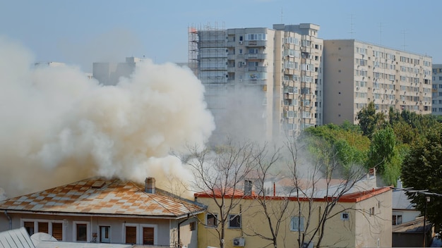 Free photo flames going out from burning house in neighbourhood. smoke emerging from roof on fire in city landscape. dangerous fumes and smog from explosion getting out of destroyed building