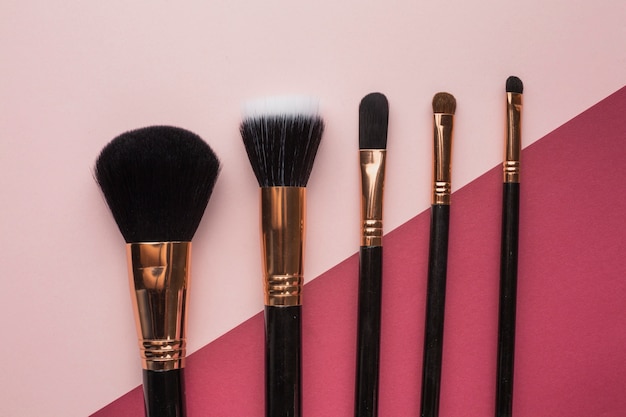 Flat lay arrangement with make-up brushes and pink background