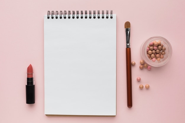 Flat lay arrangement with make-up products and notebook