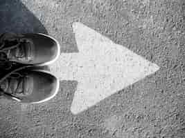 Free photo flat lay of arrow on asphalt and shoes