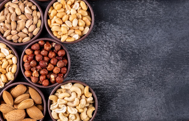 Flat lay assorted nuts and dried fruits in mini different bowls with pecan, pistachios, almond, peanut