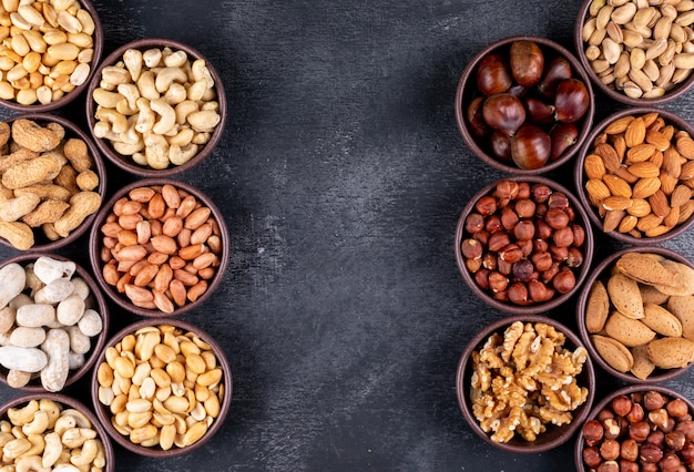 Flat lay assorted nuts and dried fruits in mini different bowls with pecan, pistachios, almond, peanut