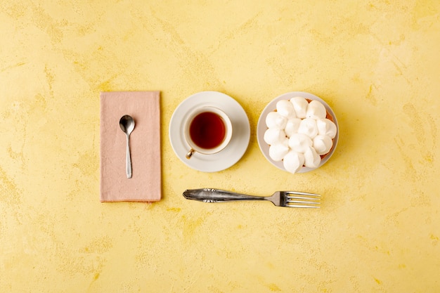 Flat lay assortment with tea and cake on yellow background