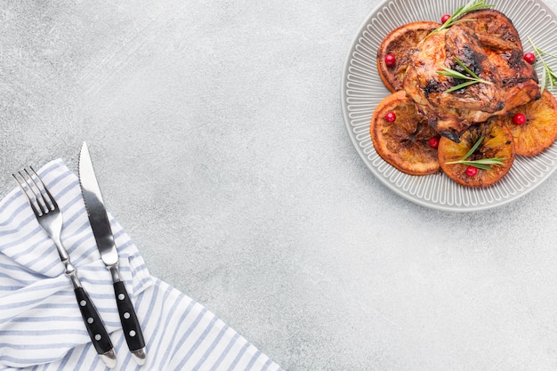 Free Photo flat lay baked chicken and orange slices on plate with kitchen towel and copy-space