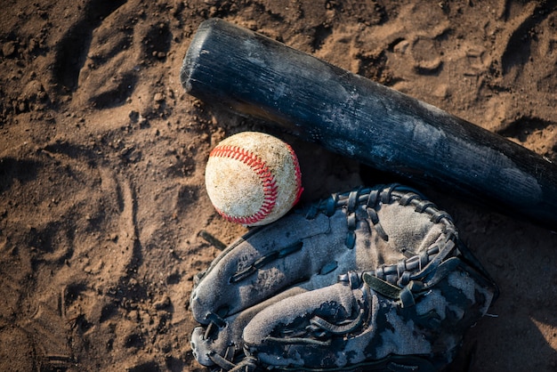 Flat lay of baseball and bat in dirt