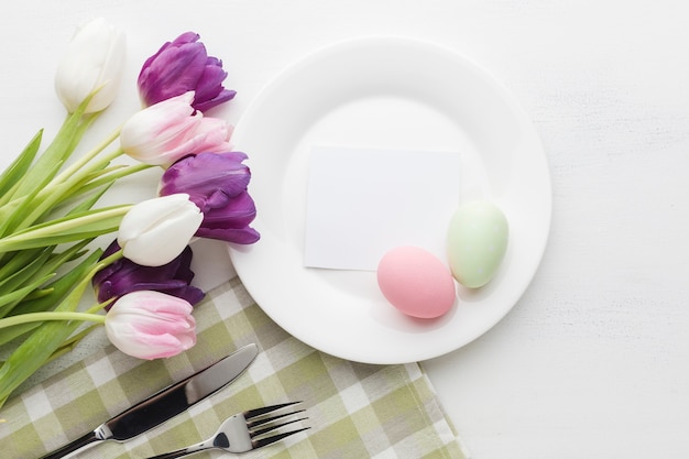 Flat lay of beautifully colored tulips with plate and easter eggs