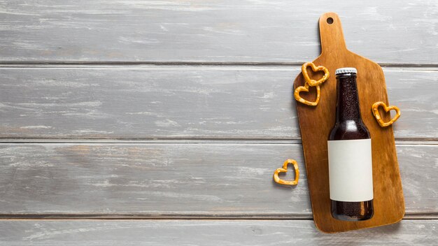 Flat lay of beer bottle with pretzels and copy space