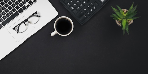 Flat lay black background with laptop coffee cup and calculator top view