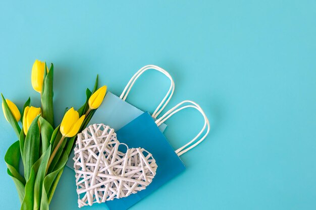 Flat lay blue background with flowers and paper bags