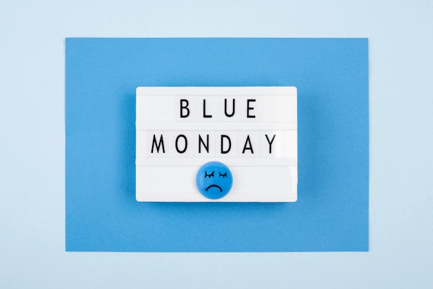 Free photo flat lay of blue monday light box with sad face